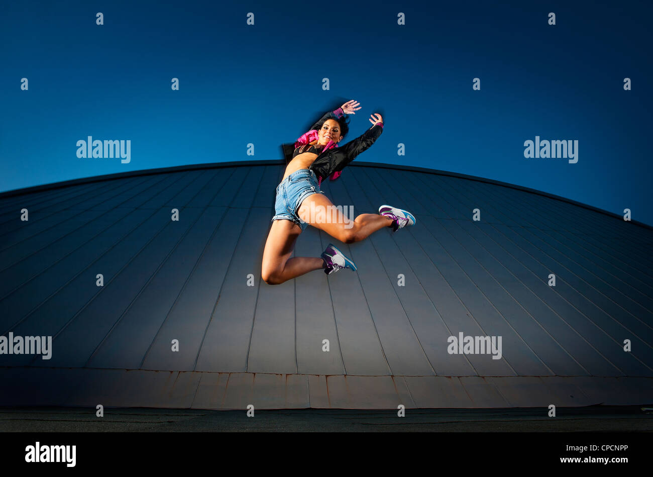 Woman jumping for joy on urban rooftop Stock Photo