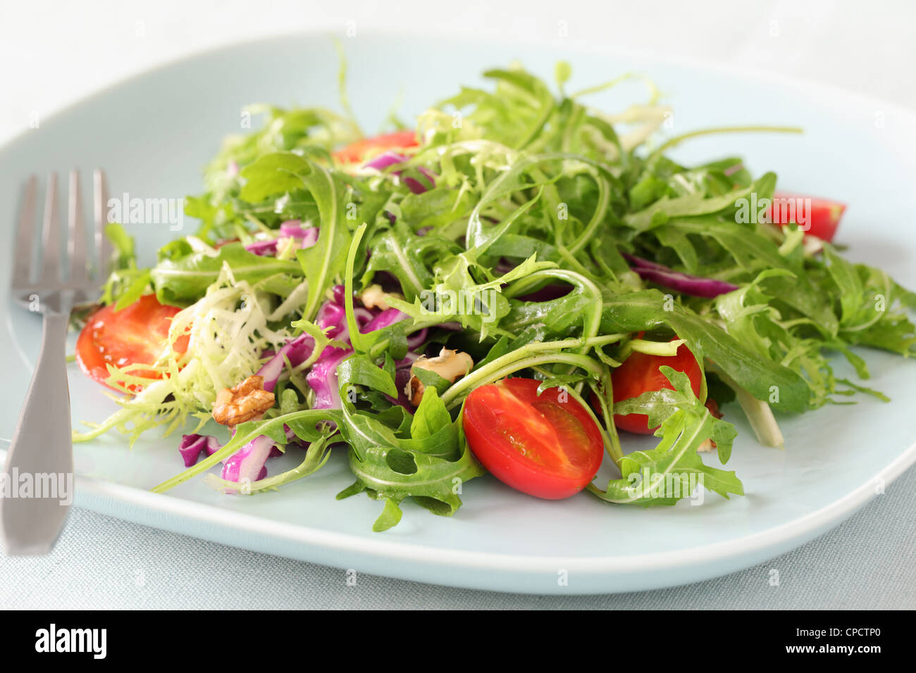 Mix salad (arugula,purple cabbage,small tomatoes) in plate Stock Photo