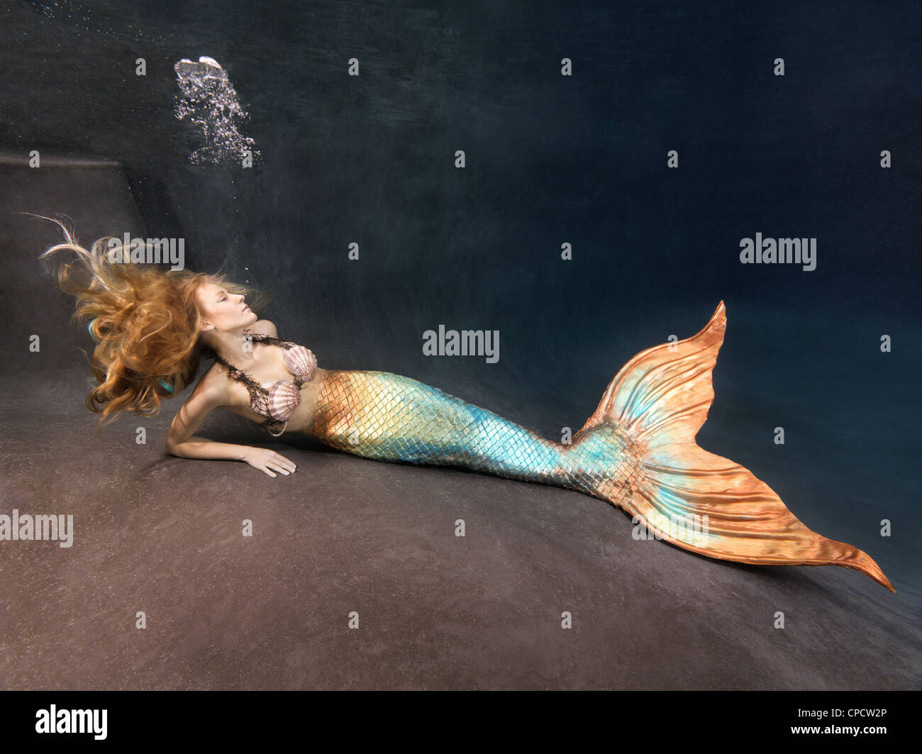 Blond mermaid laying at the bottom of a pool in Virginia Beach, Virginia. Stock Photo