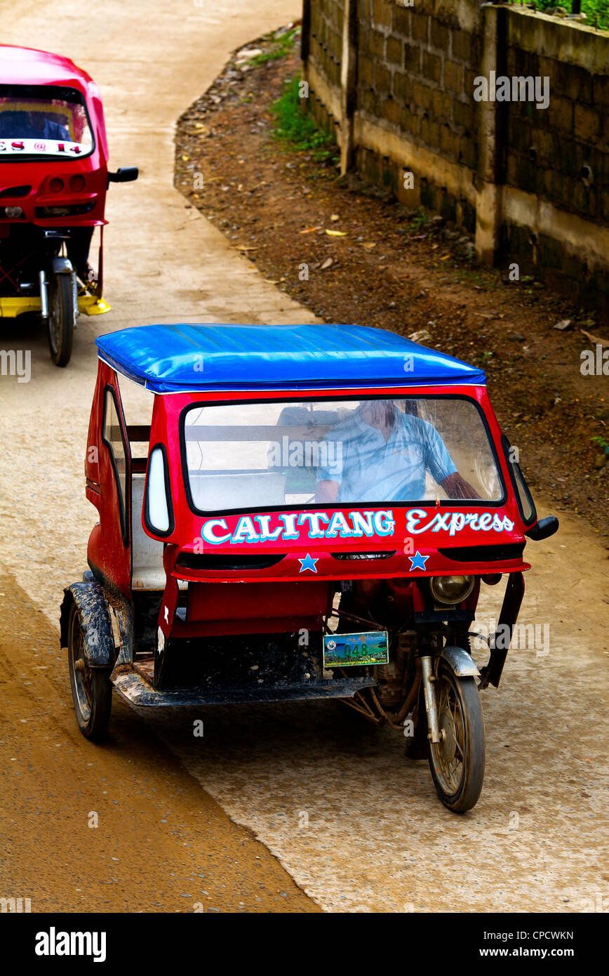 Two tricycle taxis speed down the main street of the town of El Nido on the island of Palawan in the Philippines. Stock Photo