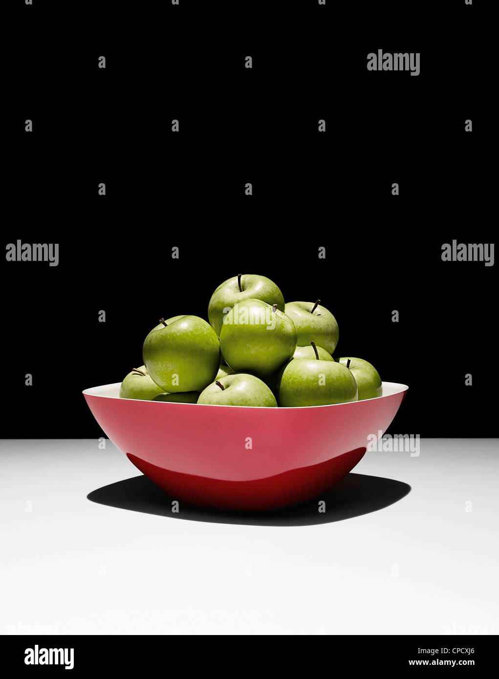 Bowl of green apples on table Stock Photo