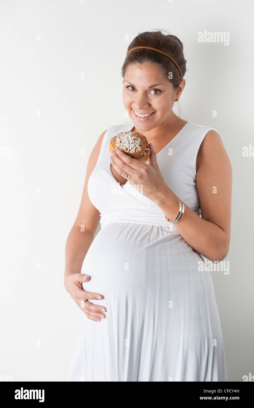 Pregnant woman eating a cinnamon roll Stock Photo Alamy