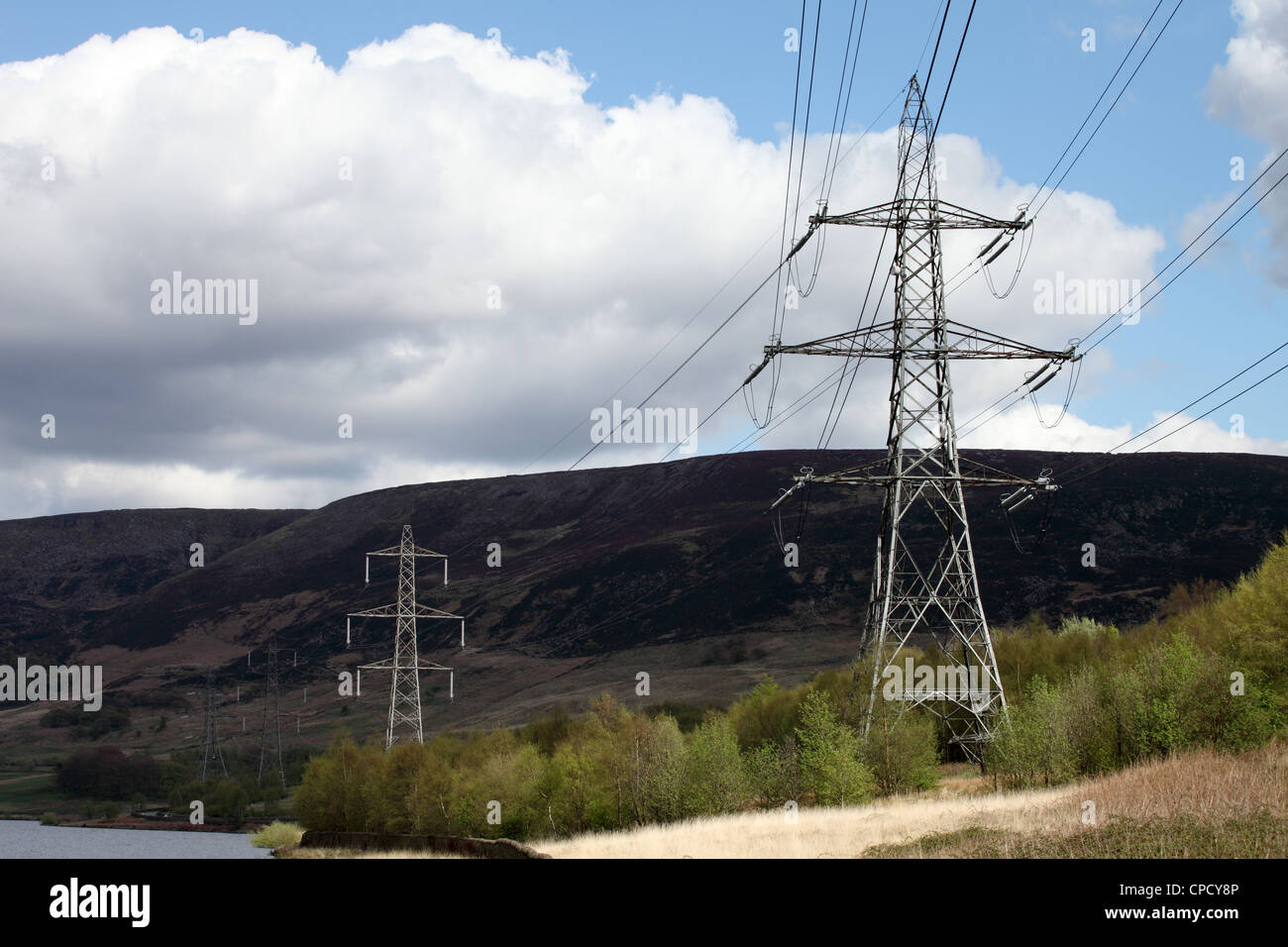 National grid a line of pylons alongside Torside reservoir within the Peak District in North Derbyshire England UK Stock Photo