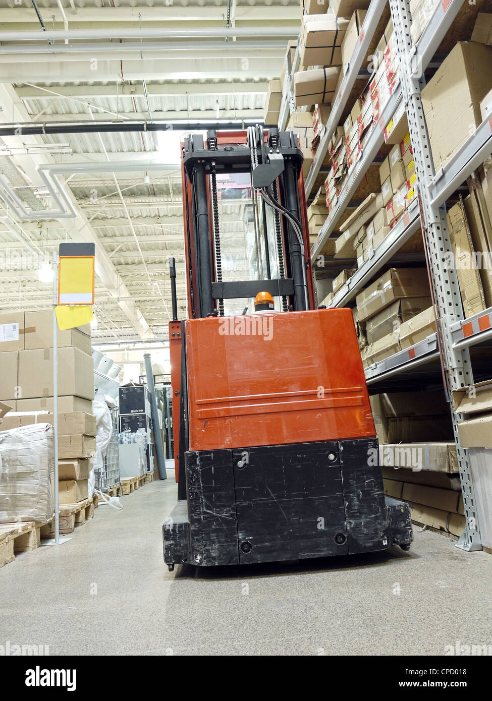 Warehouse aisle with parked forklift truck Stock Photo