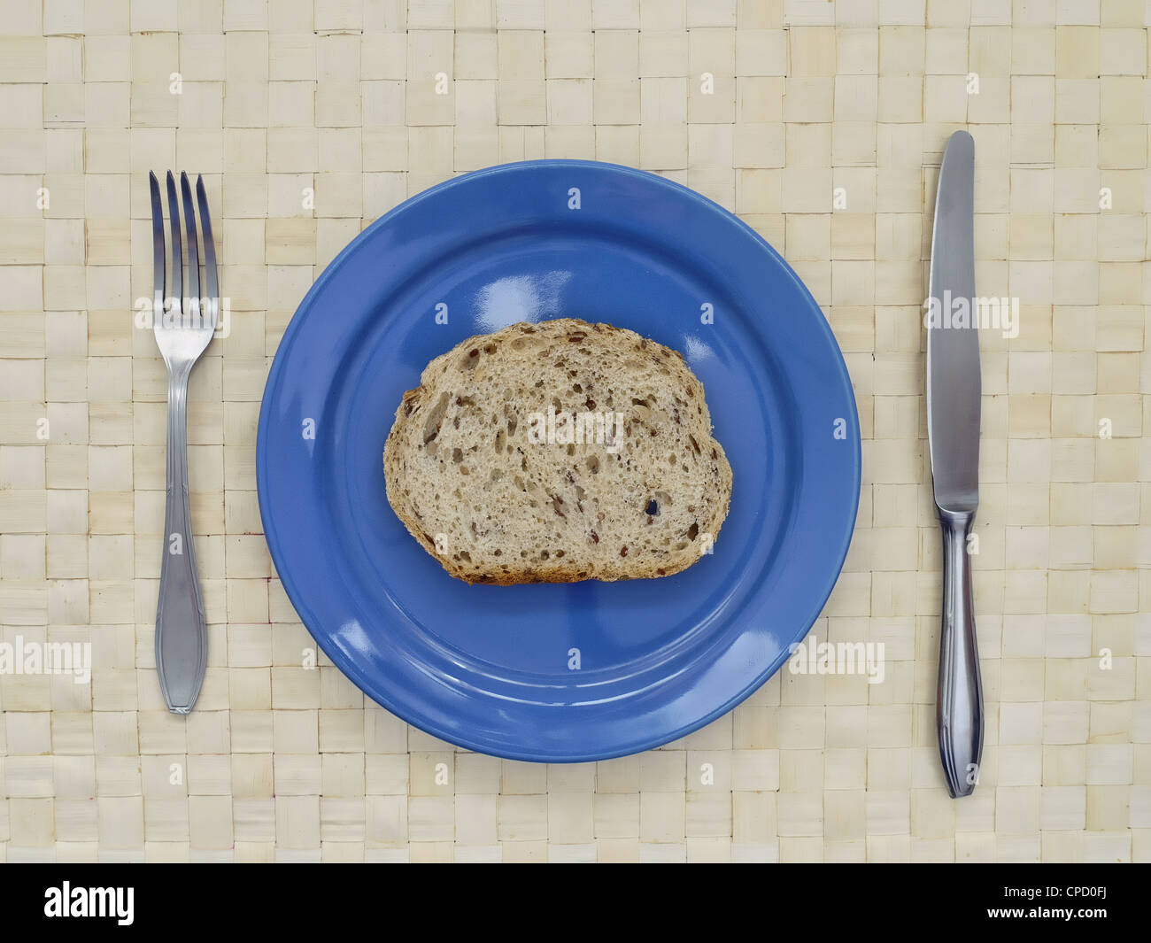 Slice of bread on blue plate with fork and knife Stock Photo