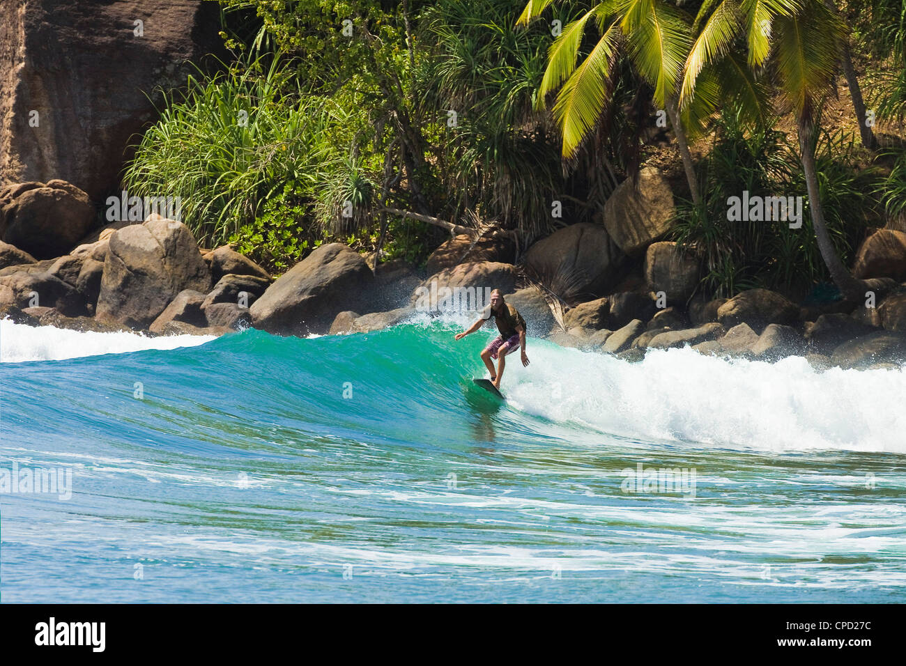 Surfer riding a wave in the western corner of the south coast beach at Mirissa, near Matara, Southern Province, Sri Lanka, Asia Stock Photo