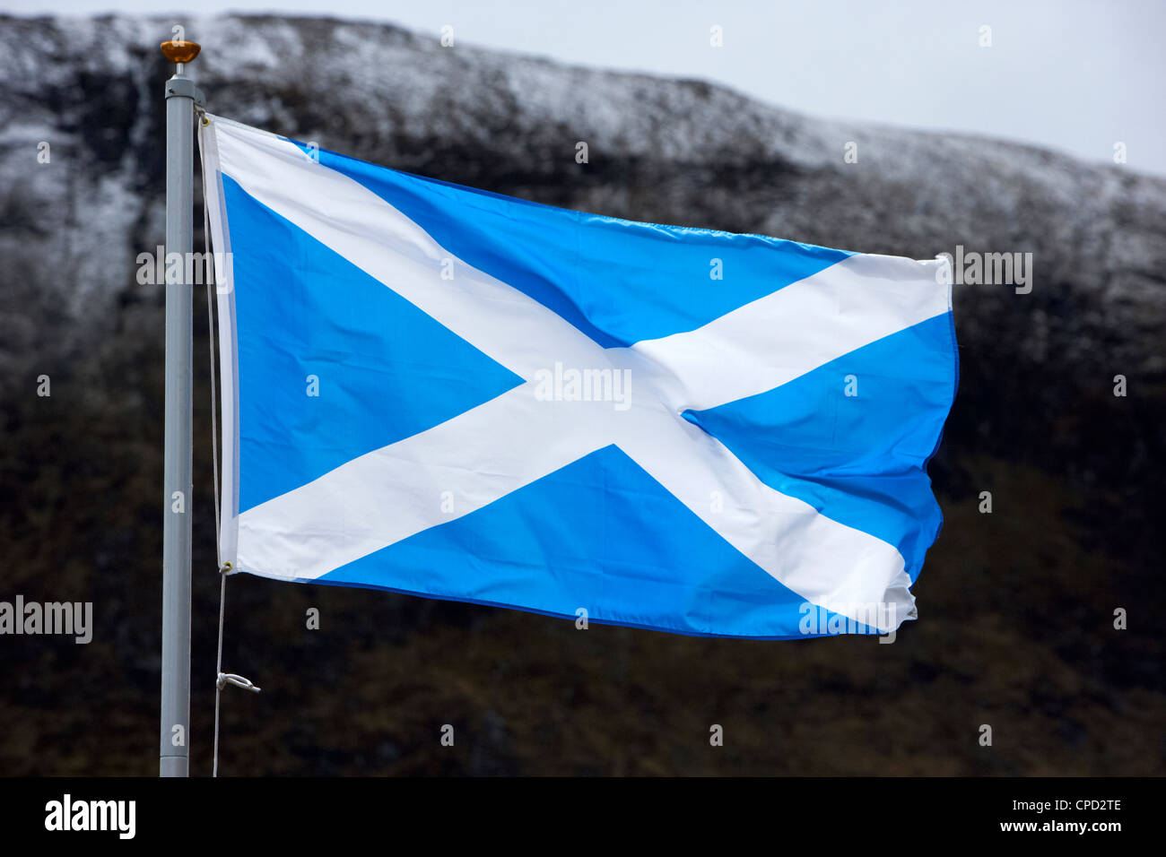 Scottish Saltire St Andrew's cross national flag flying in the highlands with snow capped mountains Scotland UK Stock Photo