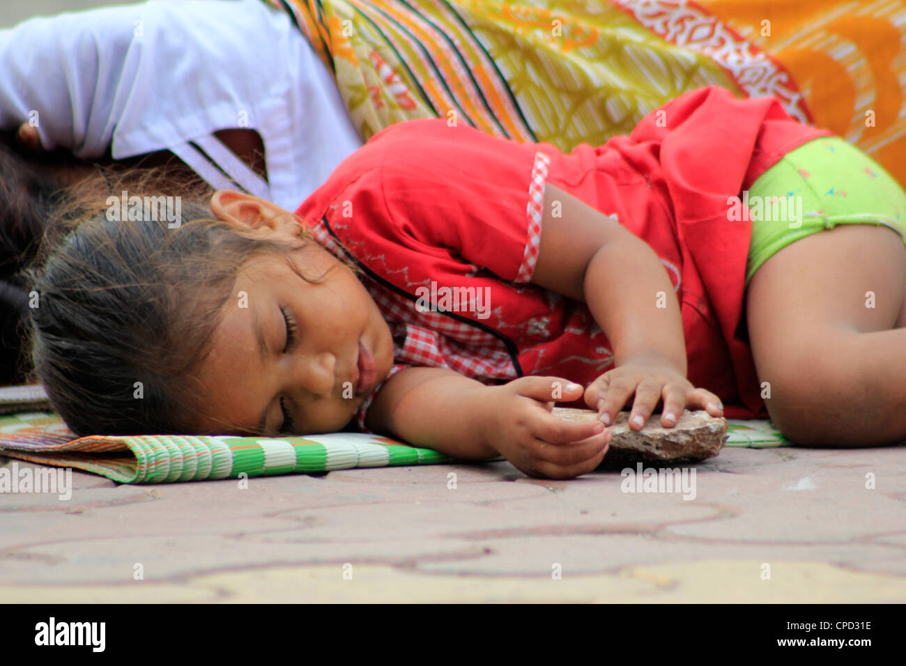 A homeless street kid sleeping on the roadside in Mumbai, India Stock Photo