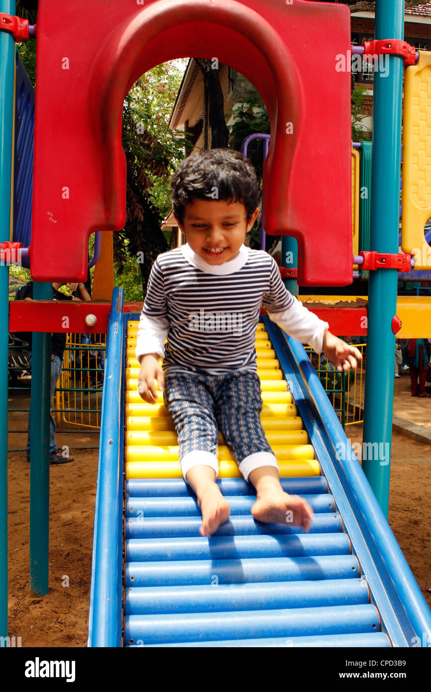Indian 3 year old going down a slide Stock Photo