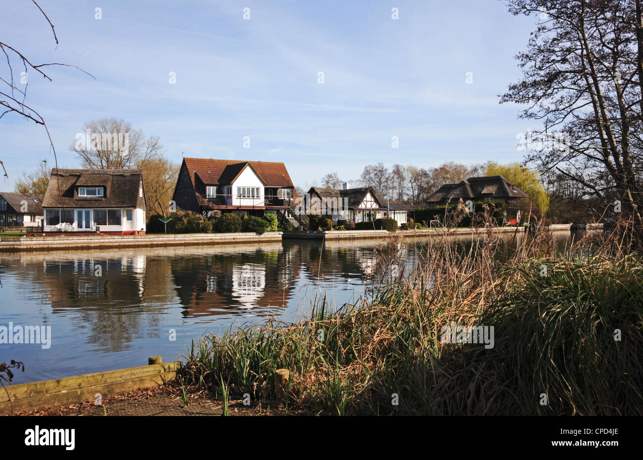 A view of riverside properties with reflections by the River Bure on