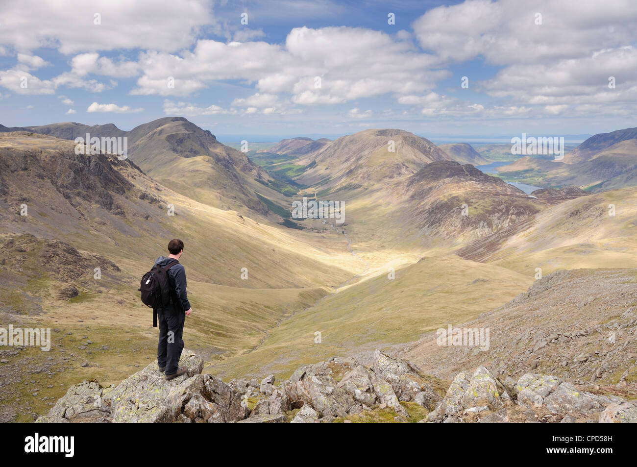 Walker on summit of Green Gable in the English Lake District, looking down Ennerdale Valley towards Pillar and Haystacks Stock Photo