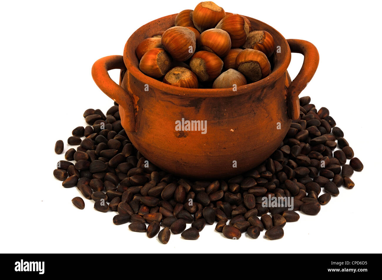 pot with hazelnuts, pine nuts surrounded, isolated, close-up Stock Photo