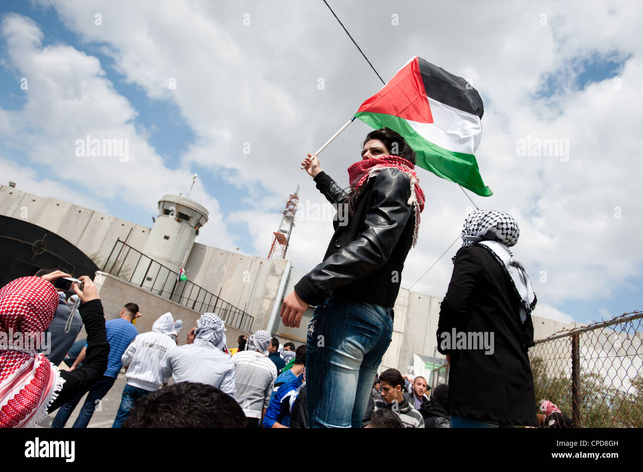 A Palestinian young woman waves a flag near the Bethlehem checkpoint during Land Day protests in Bethlehem. Stock Photo