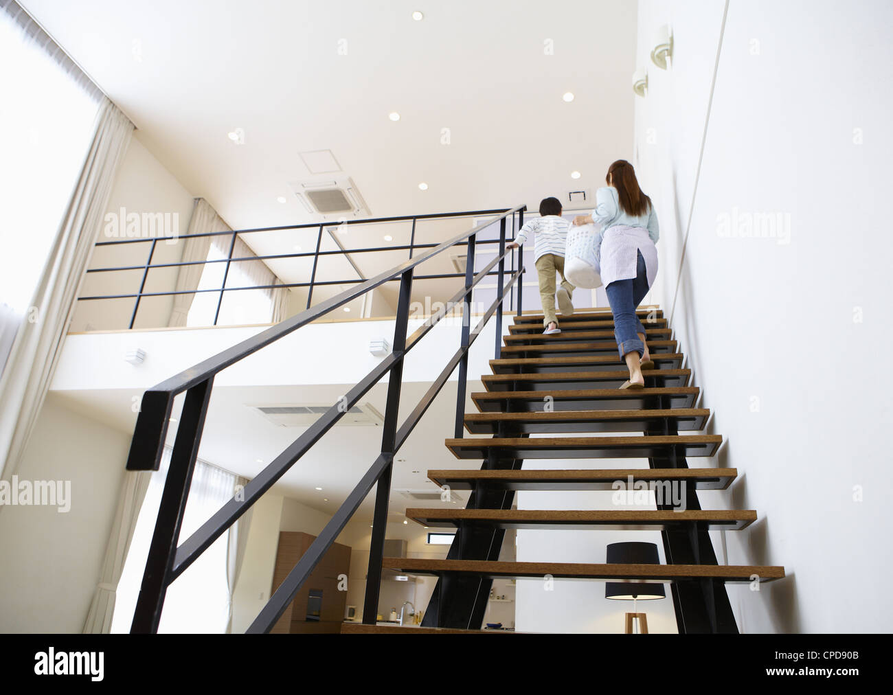 Mother and son holding a laundry basket and going up stairs Stock Photo