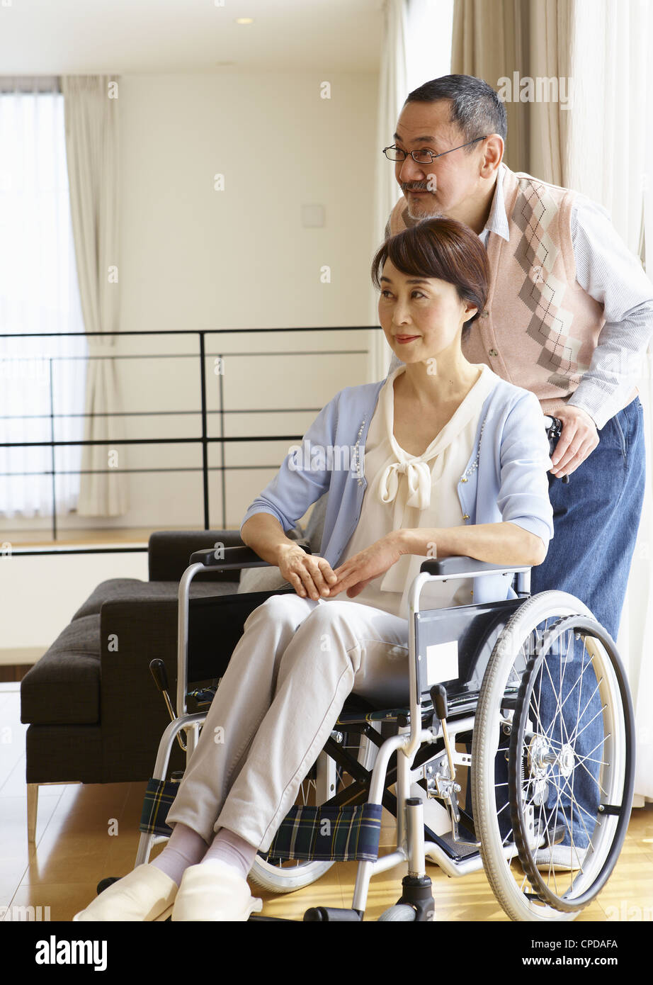 Senior man standing by his wife in a wheelchair Stock Photo - Alamy