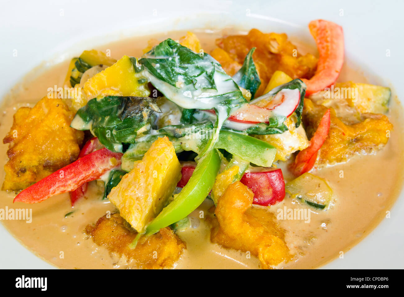 Thai Friend Salmon Fish Fillet in Red Curry with Basil Leaves Pumpkin and Bell Peppers Closeup Stock Photo