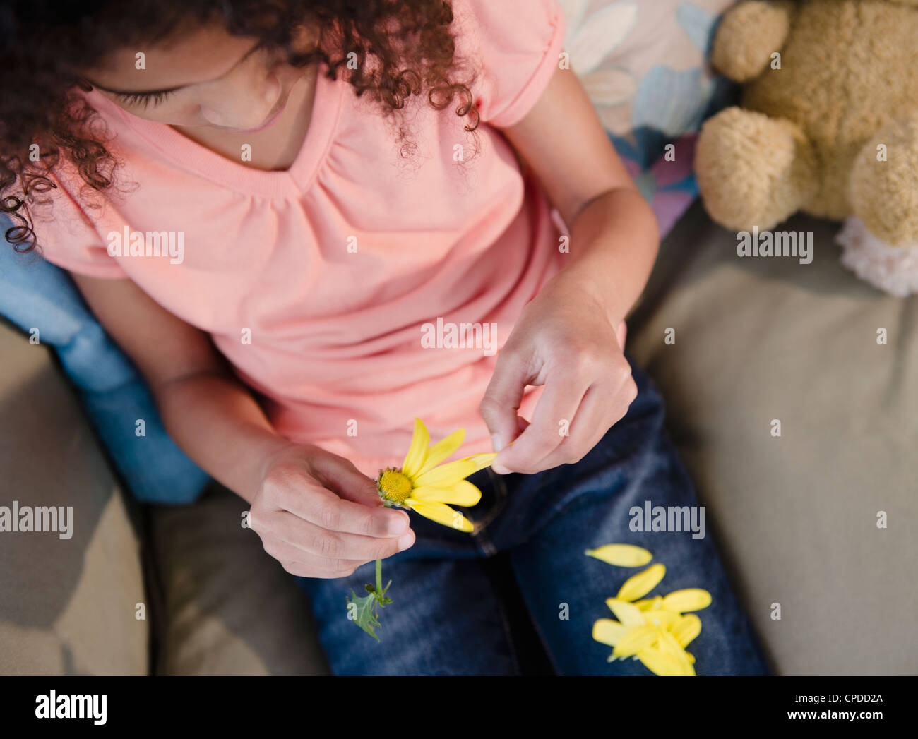 Mixed race girl picking petals from flower Stock Photo