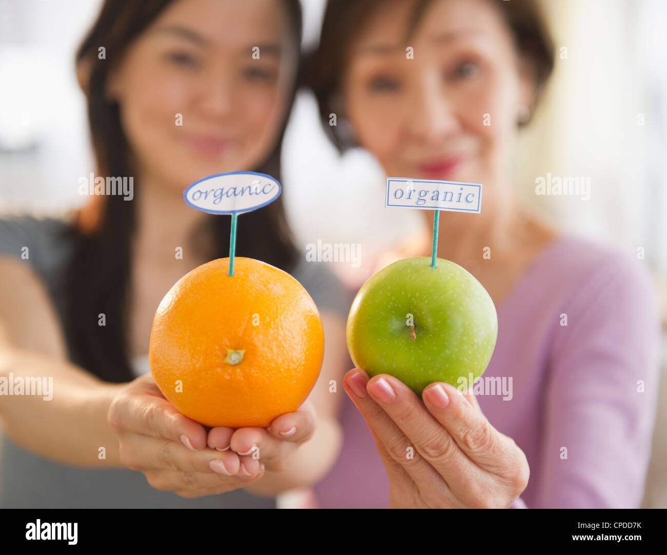 Japanese mother and daughter holding fruit with organic label Stock Photo