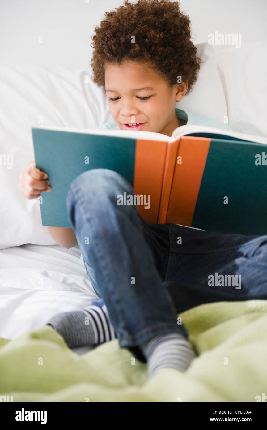 Black boy reading book in bed Stock Photo