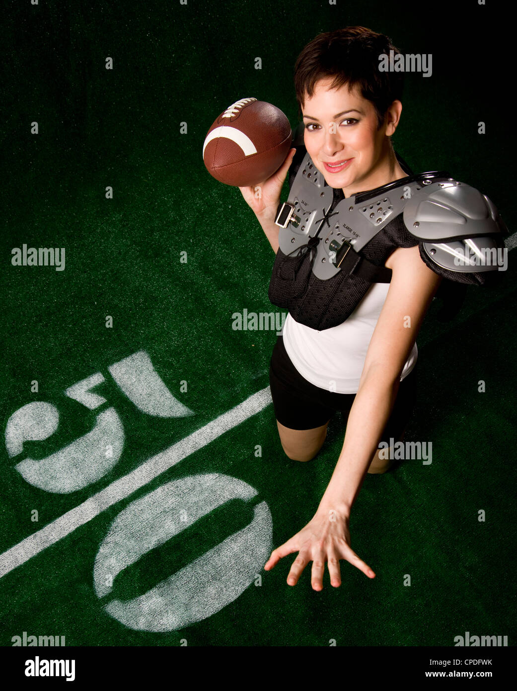 A female football player smiles as she throws a forward pass Stock