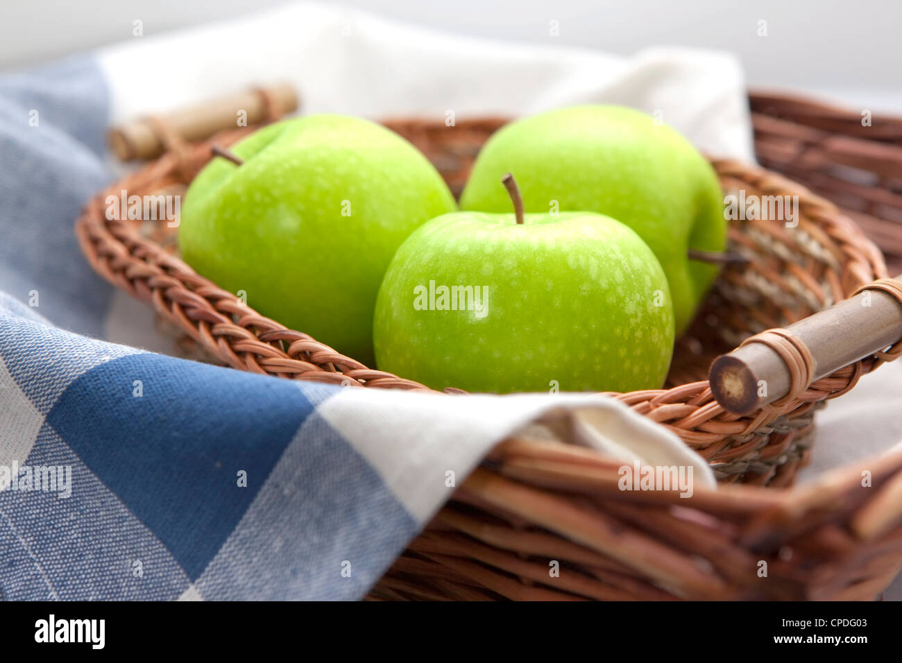 Green apples in the brown wicker basket with a blue gingham cloth Stock ...