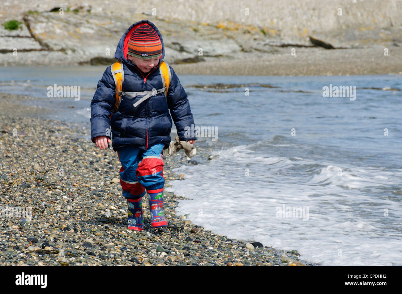 A young boy on a pebble beach Stock Photo
