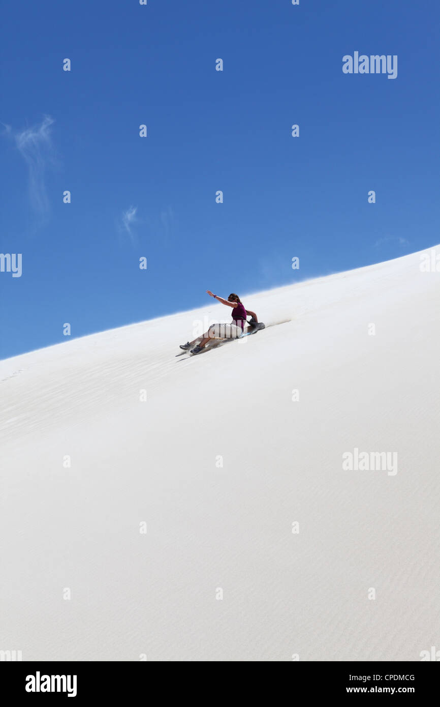 A woman rides a sandboard, sandboarding on a white sand dune, Lancelin, Western Australia, Australia, Pacific Stock Photo