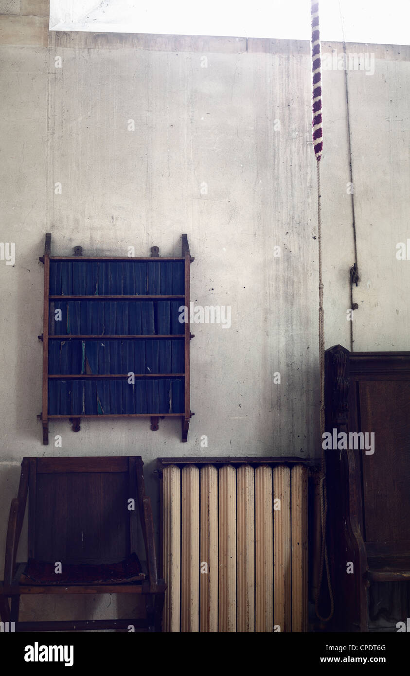 Church interior with bookcase for Book of Common Prayer, chair and radiator. Stock Photo