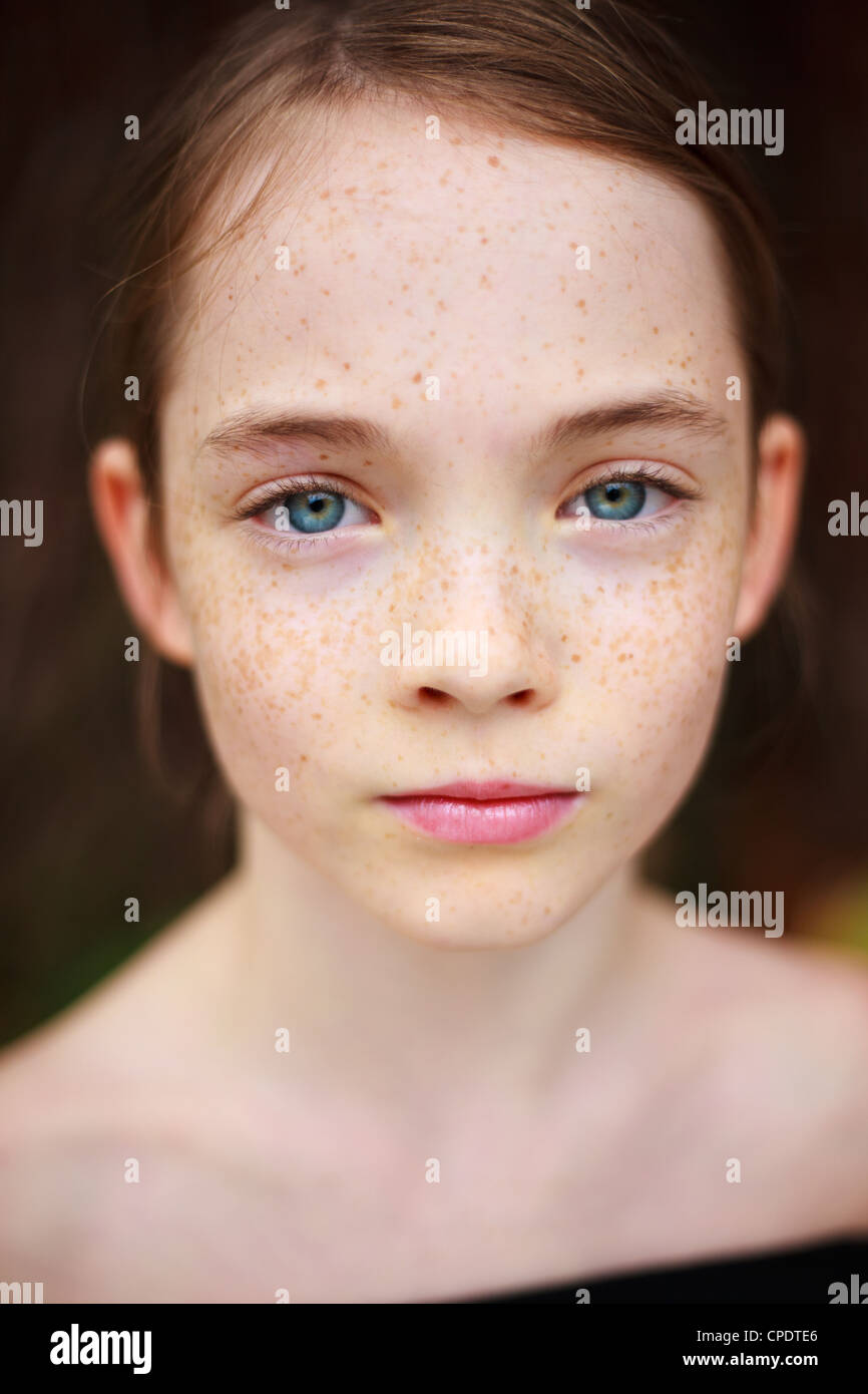 A close up on a young freckled girl's face, looking at the camera. Stock Photo