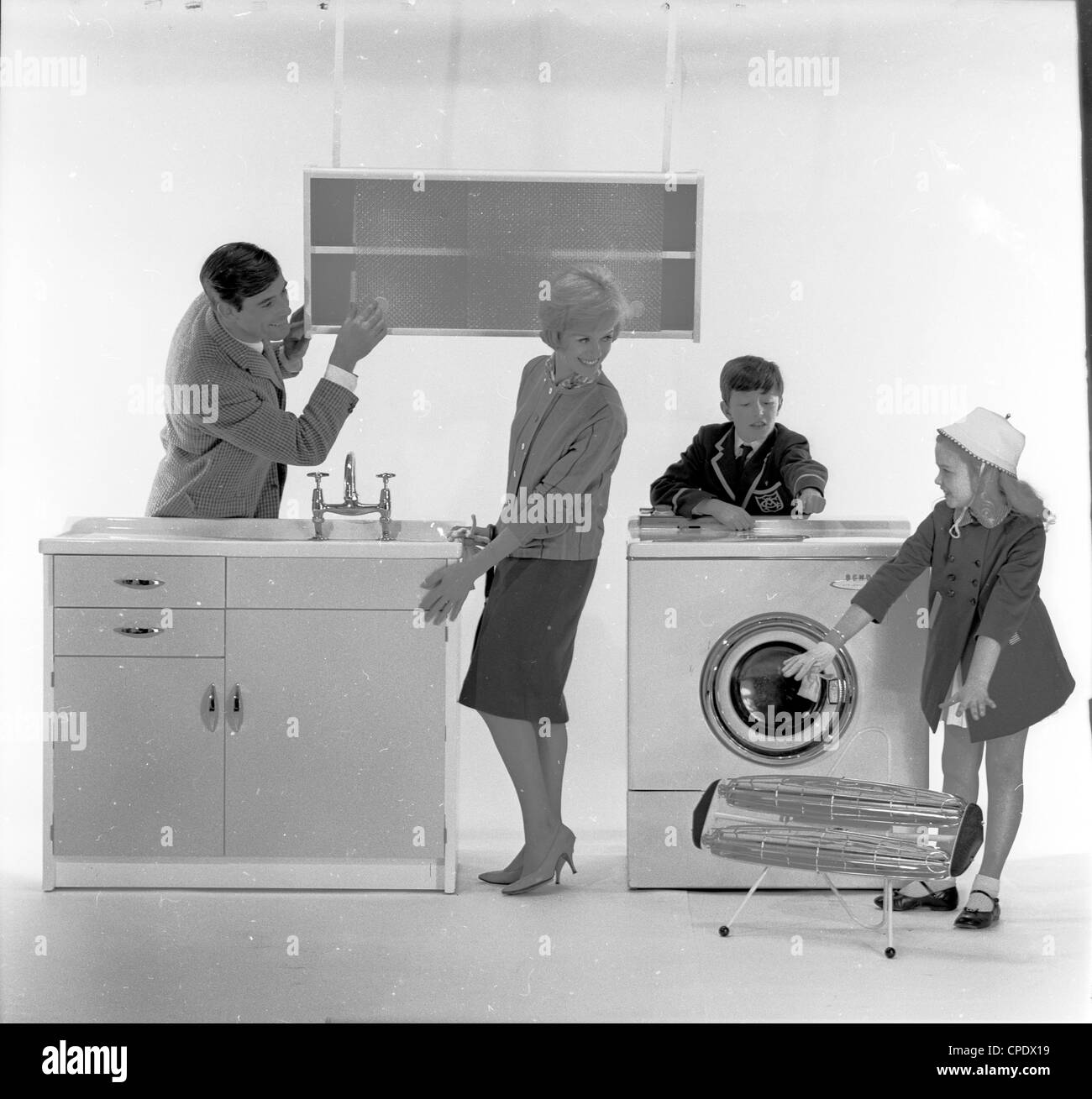 1960s. Photo shoot advertising new kitchen appliances. Mother, father and son and daughter pose in a photographic studio admiring the new  kitchen units and home appliances now available for the modern home. Stock Photo