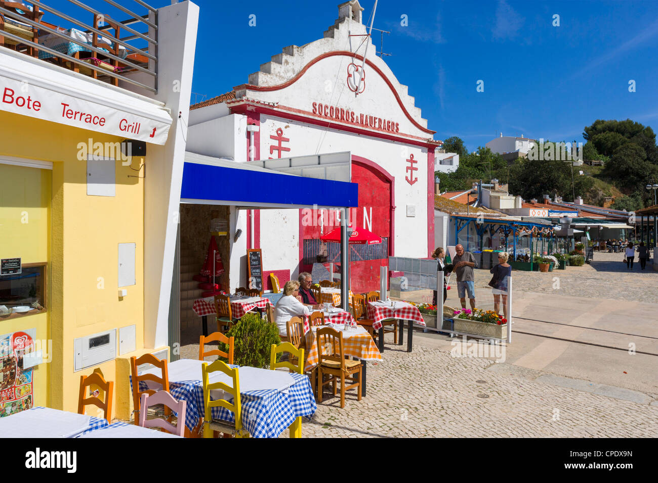 Seafront restaurant by the harbour in the resort of Alvor with lifeboat station behind, near Portimao, Algarve, Portugal Stock Photo