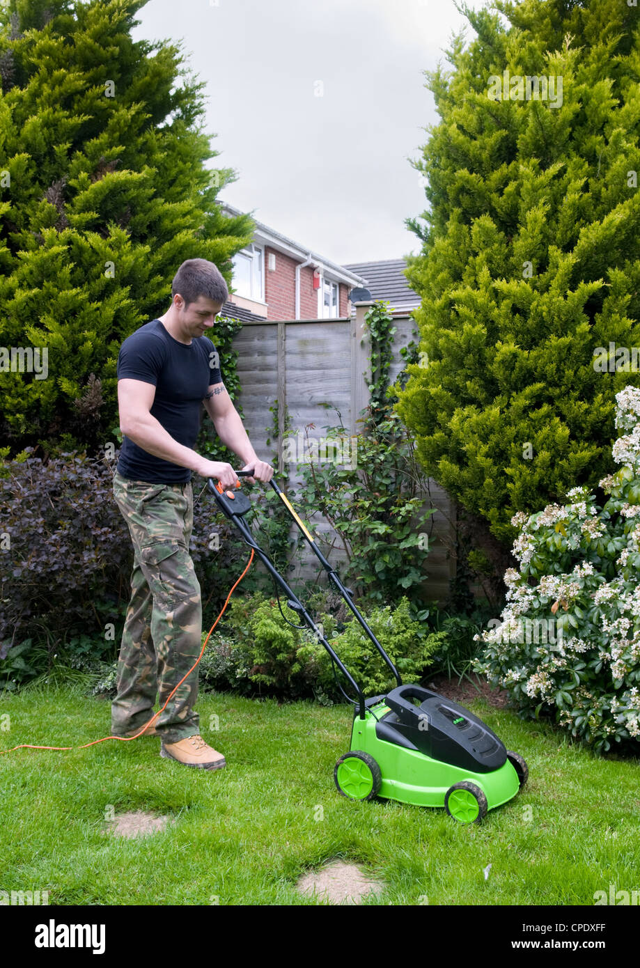 Caucasian man mowing lawn in garden in Bristol, UK Stock Photo