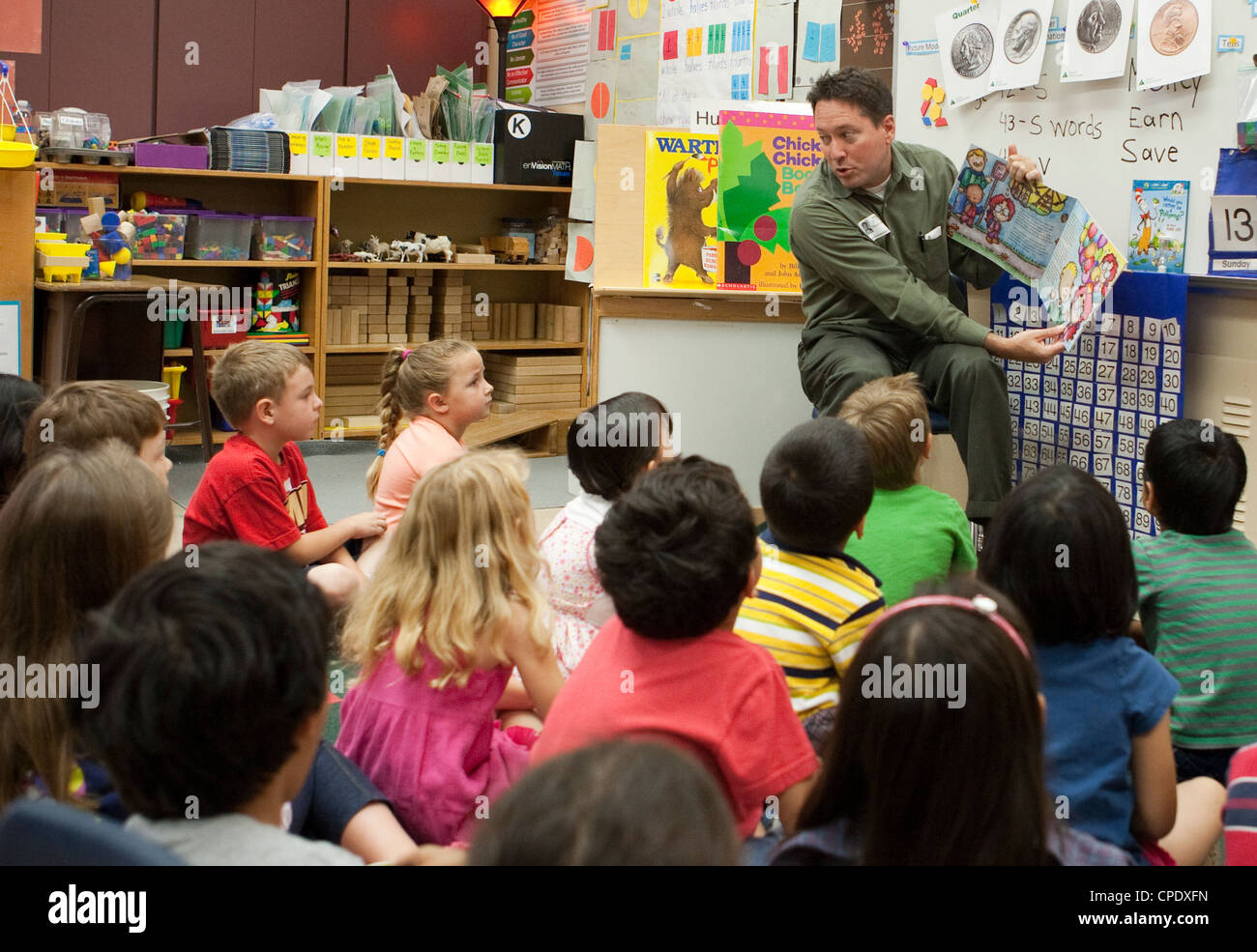 Anglo male teacher in training, reads a story book to kindergarten students at a Texas public school Stock Photo