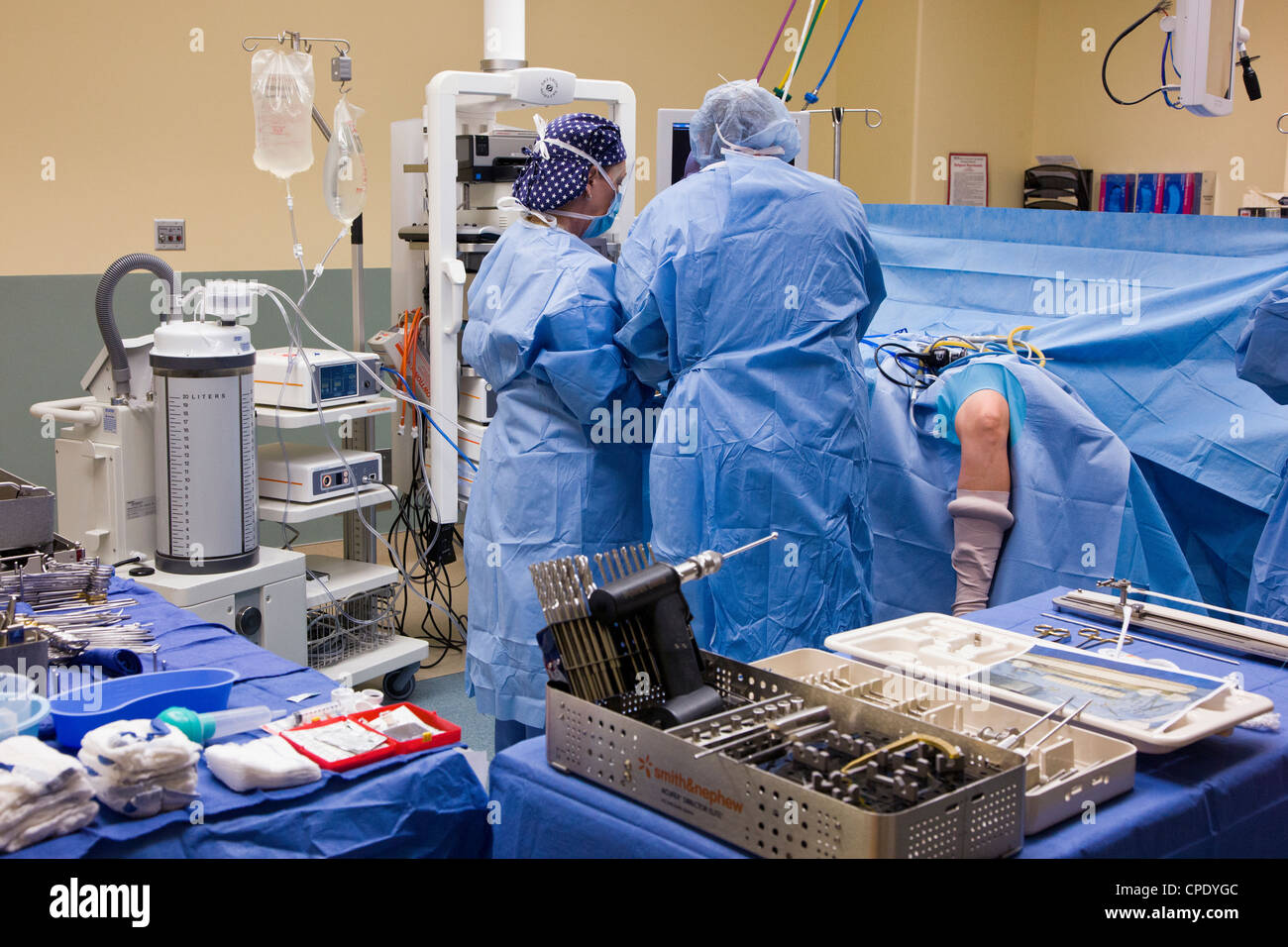 Orthopedic surgeon preparing patient for arthroscopic knee surgery in a hospital operating room suite Stock Photo