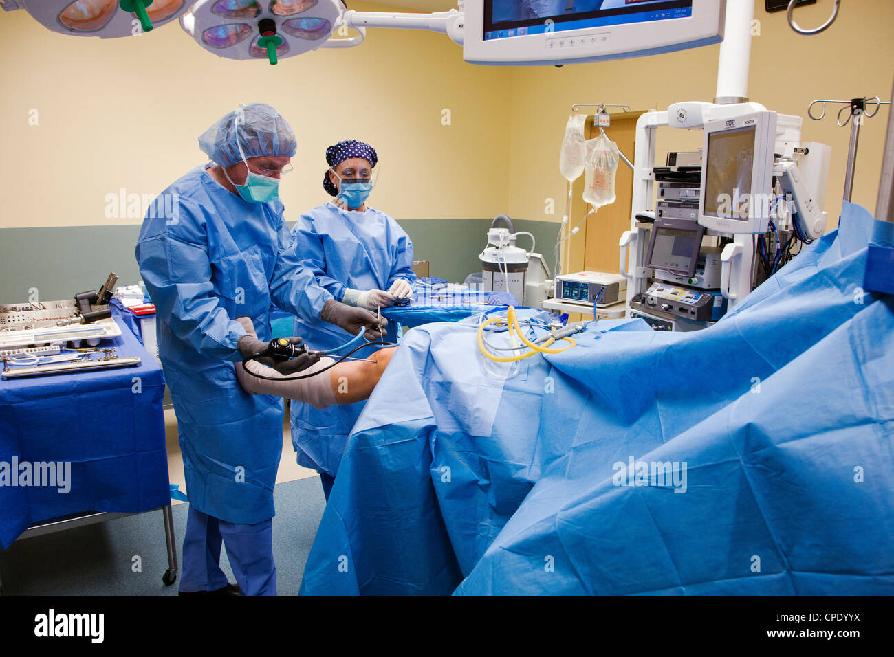 Orthopedic surgeon preparing patient for arthroscopic knee surgery in a hospital operating room suite Stock Photo