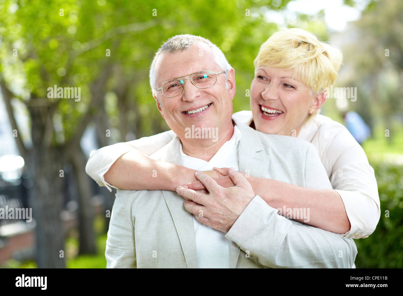 Portrait of happy mature woman hugging her husband outside Stock Photo