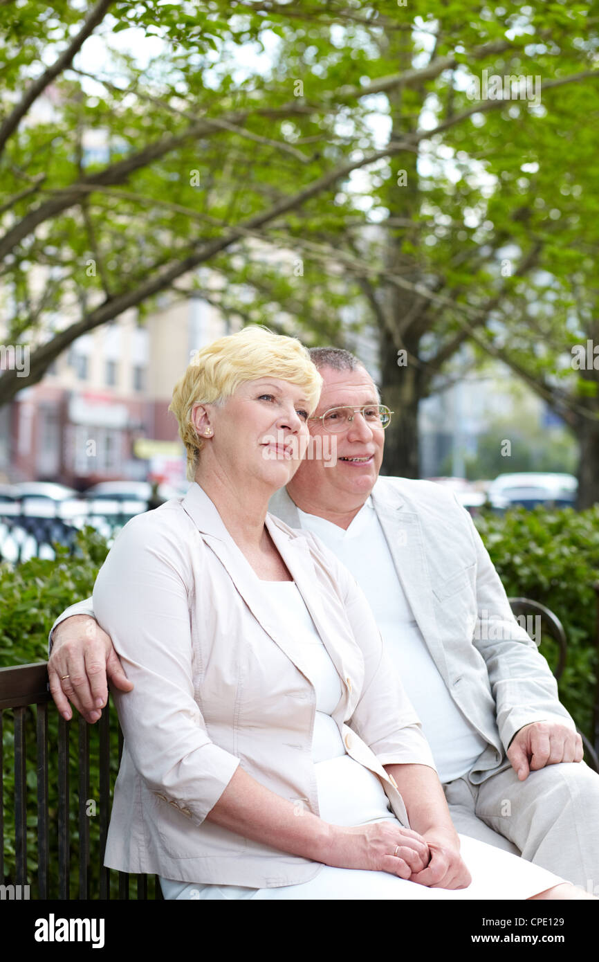 Mature couple sitting on bench in park in summer Stock Photo