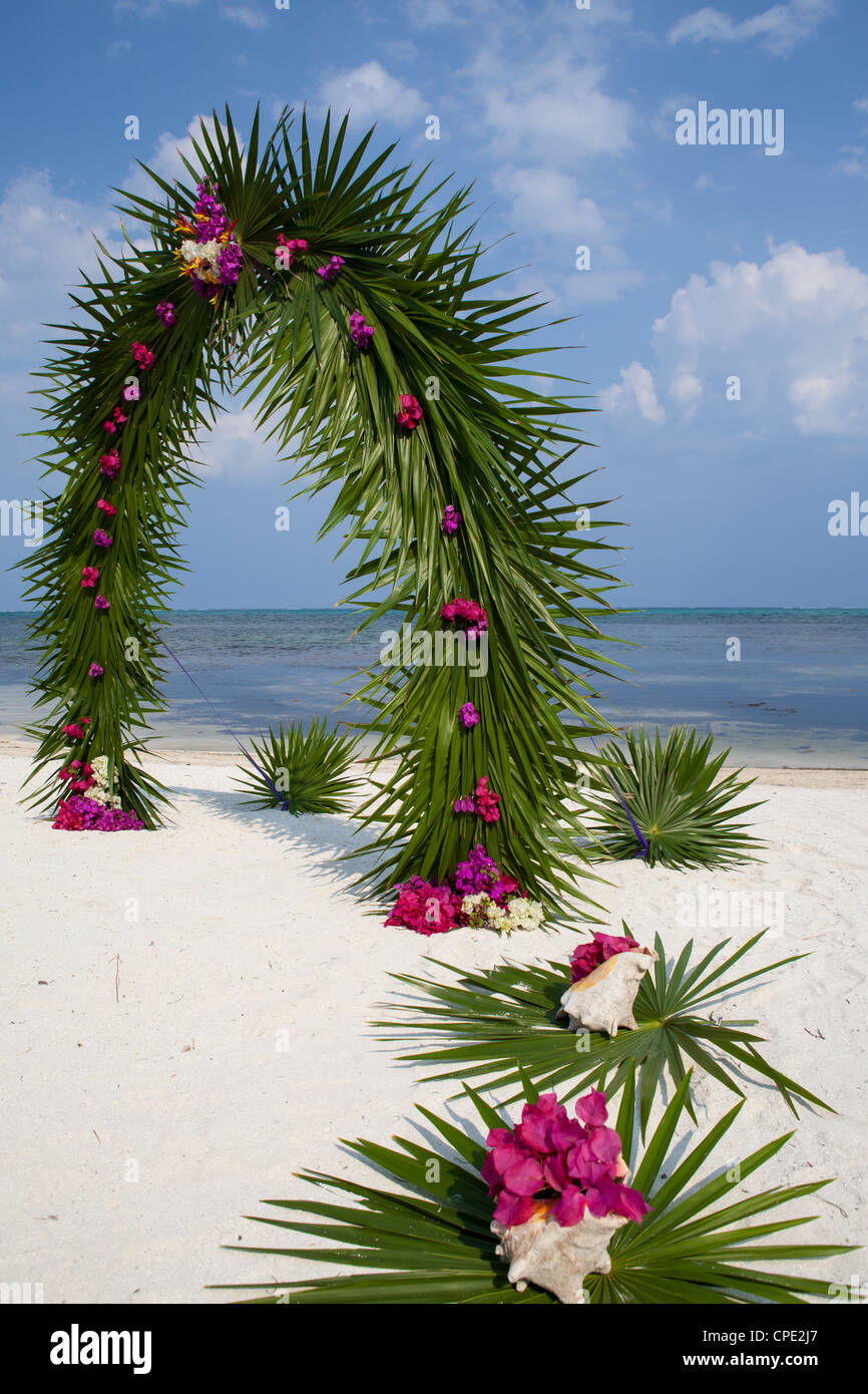 Belize Beach Wedding Arch of Palm Fronds and Pink Bougenvellia Stock Photo