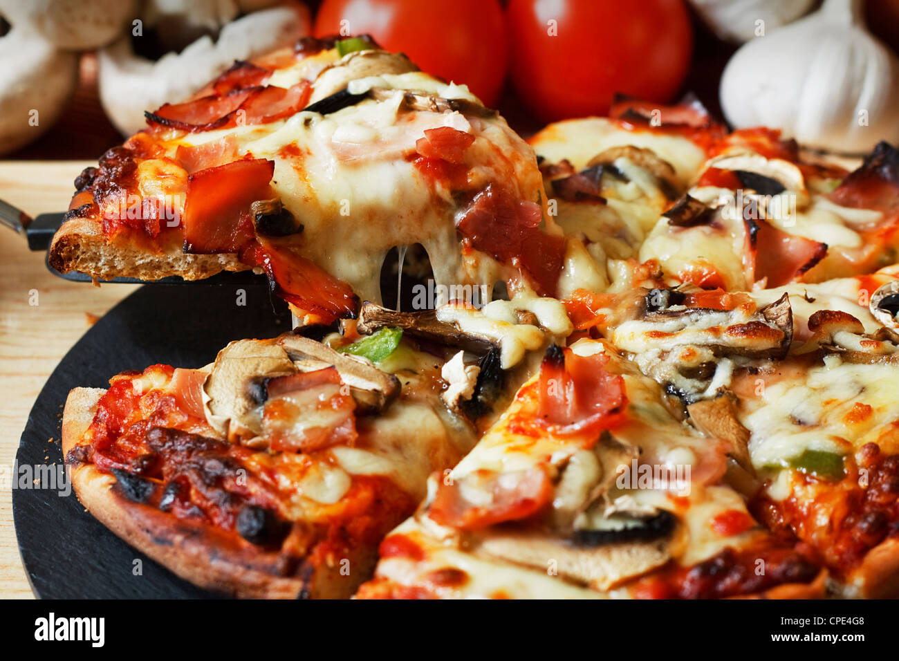 serving slice of ham and mushroom pizza with close up on stringy melted mozzarella cheese Stock Photo