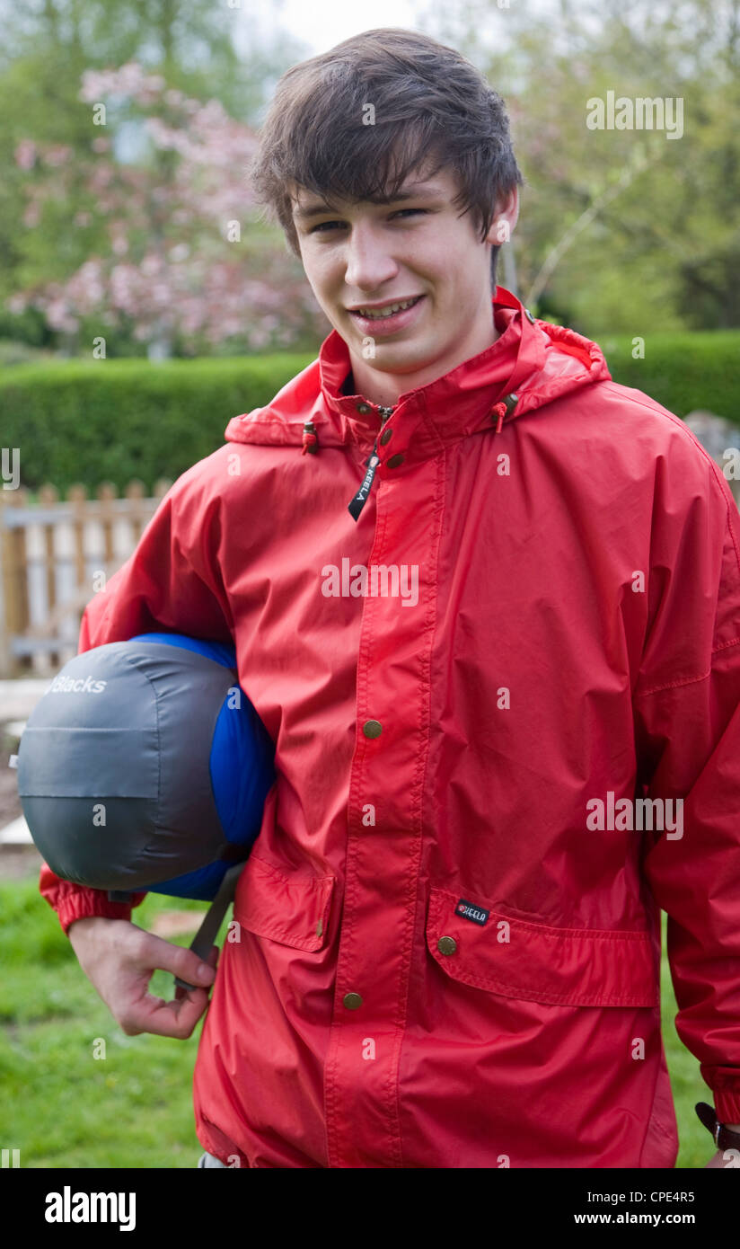 Model released image of young man wearing red kagoule jacket and holding sleeping bag Stock Photo Alamy