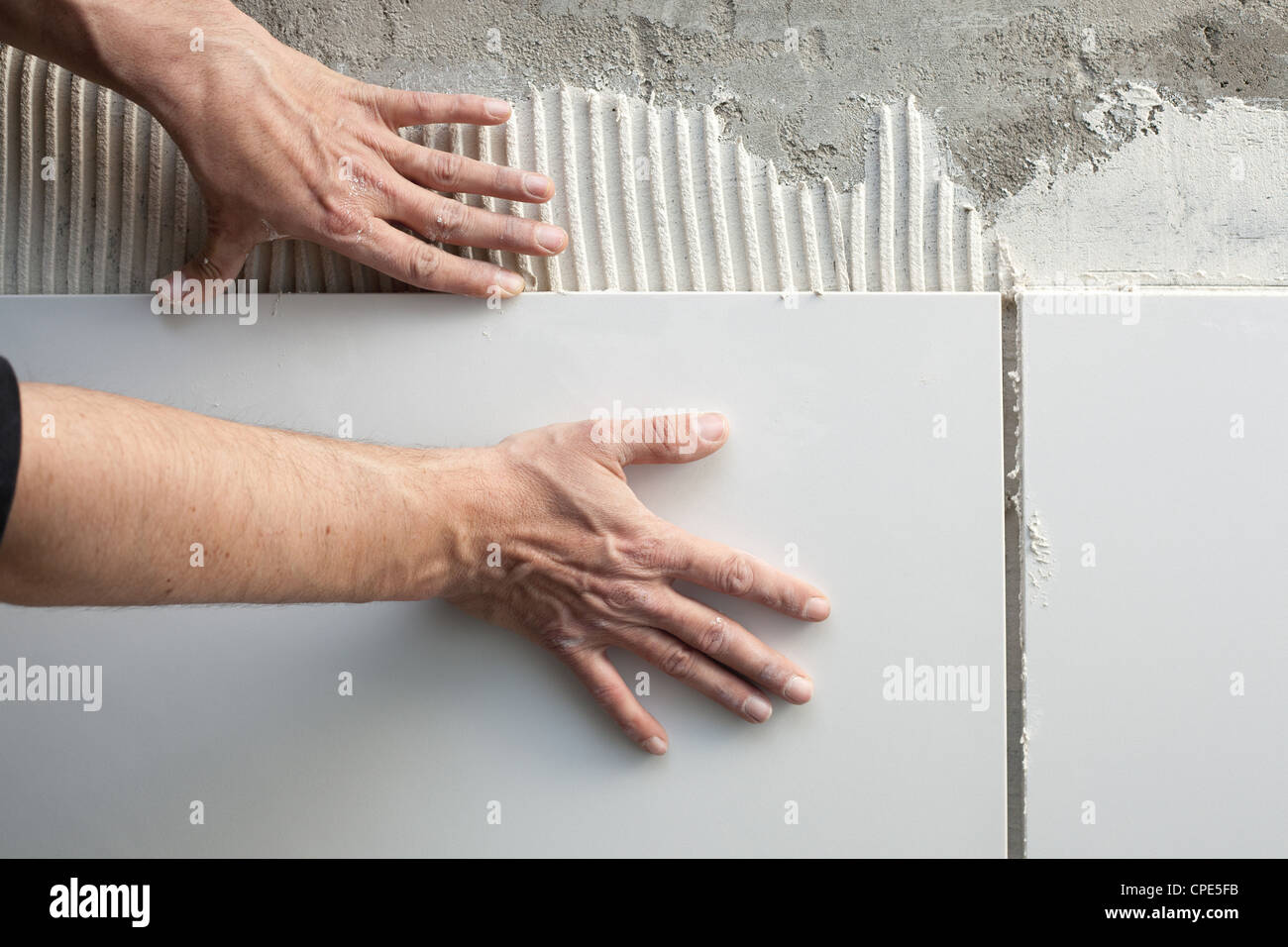 construction mason man hands on tiles work with notched trowel cement mortar Stock Photo