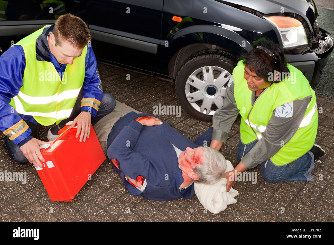 Car crash victim being helped by paramedics (the sleeve badges have been replaced by a non existing logo) Stock Photo