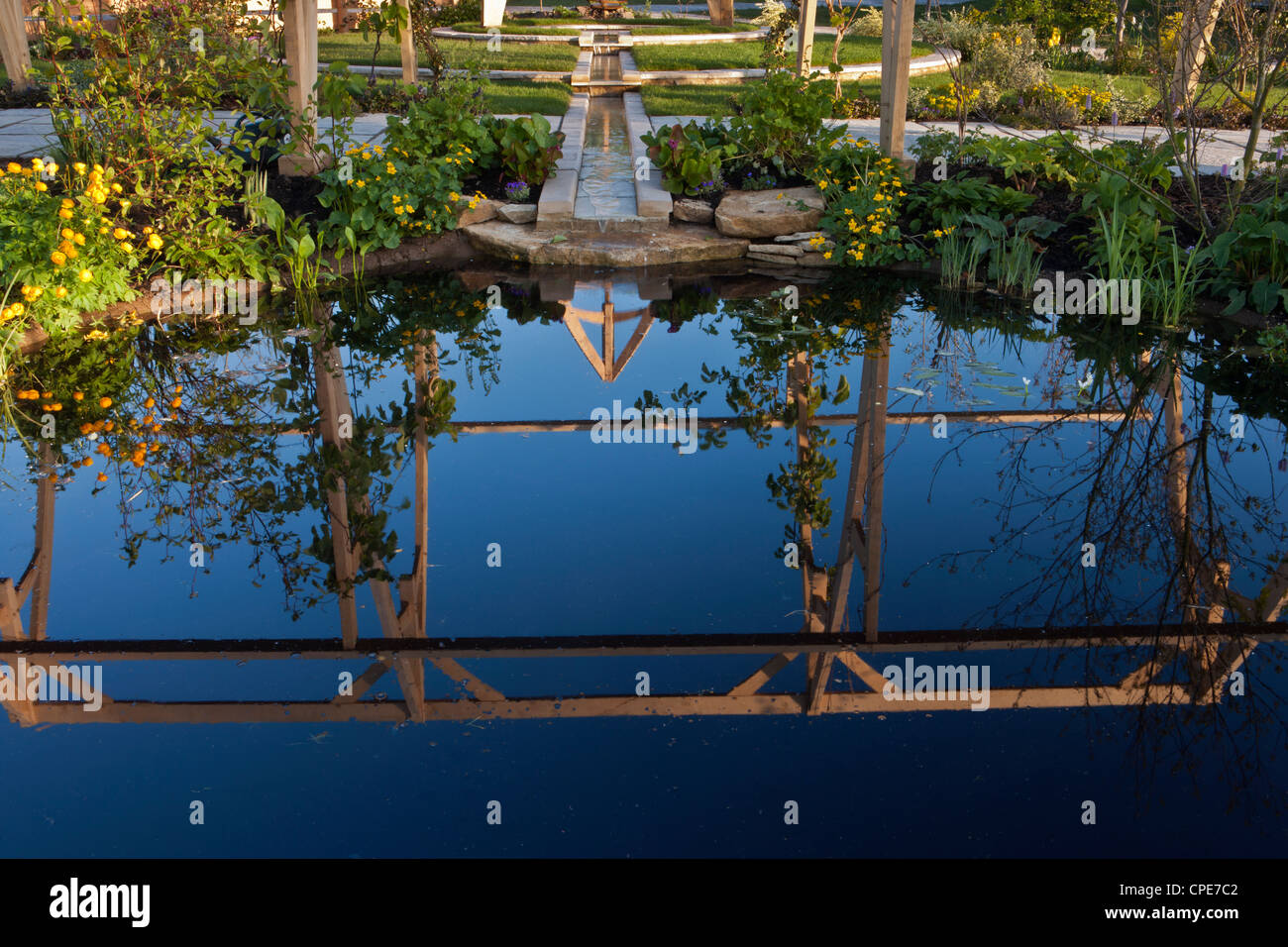 Garden with garden rill water feature made from stone in spring and planting of water marginal plants  UK Stock Photo