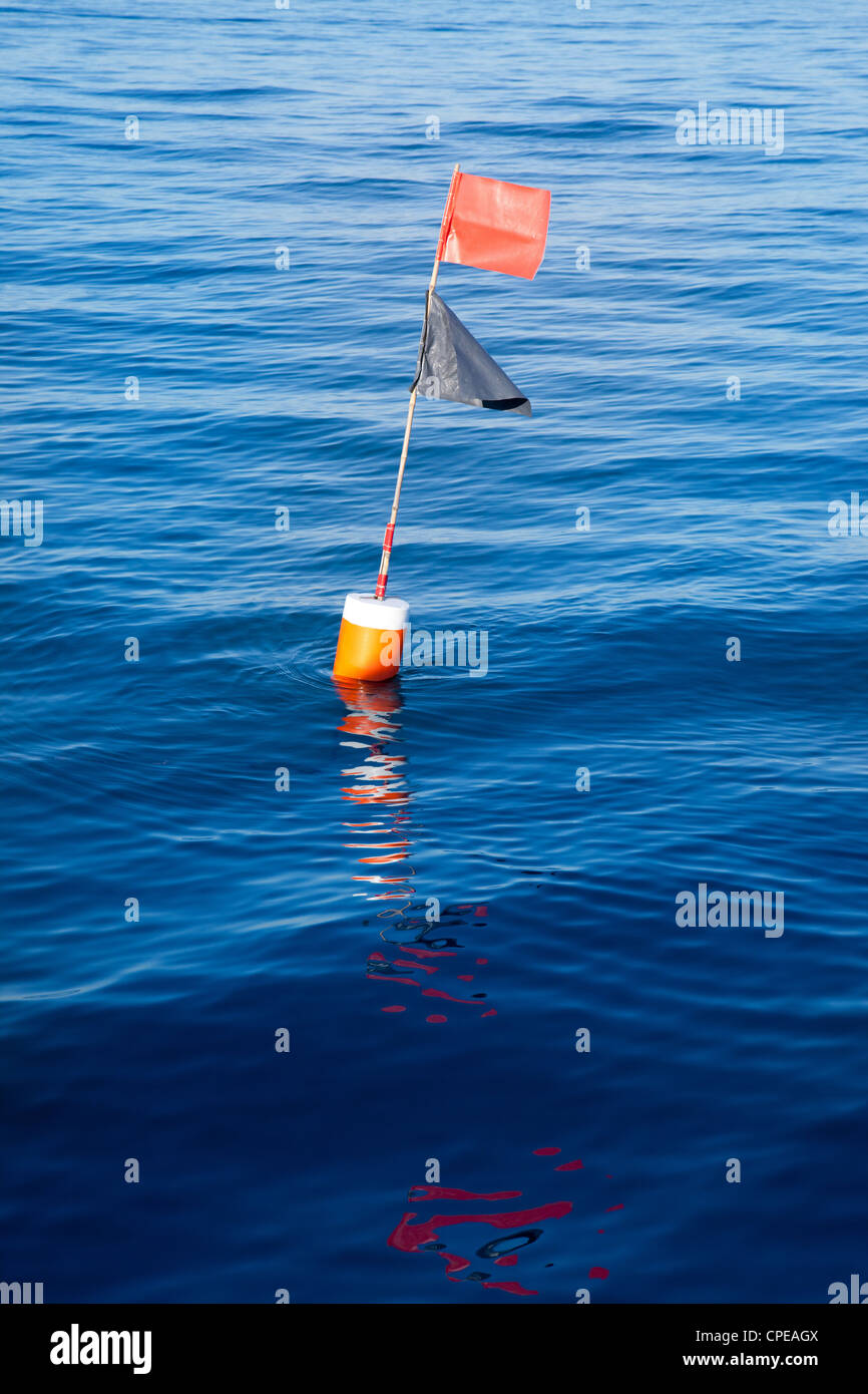 Longliner and trammel net buoy with flag pole in blue sea Stock