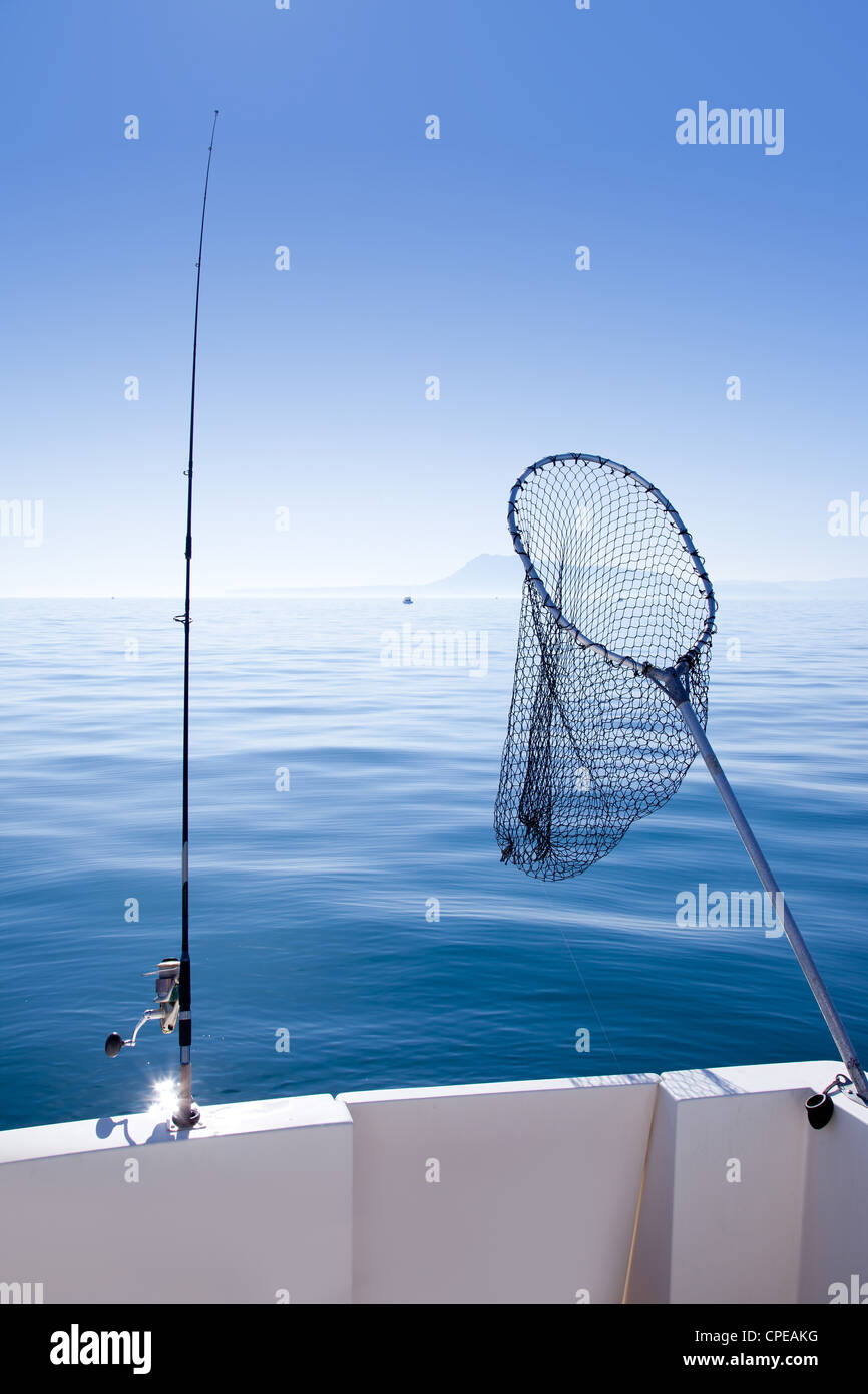 boat fishing rod and landing net in mediterranean blue sea Stock Photo