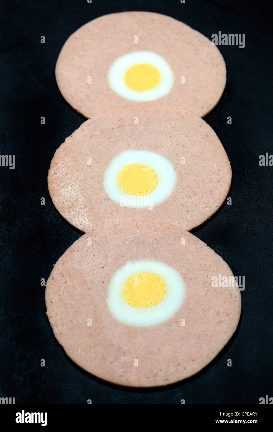 Sliced sausage meat with boiled egg in the middle on a black background Stock Photo Alamy
