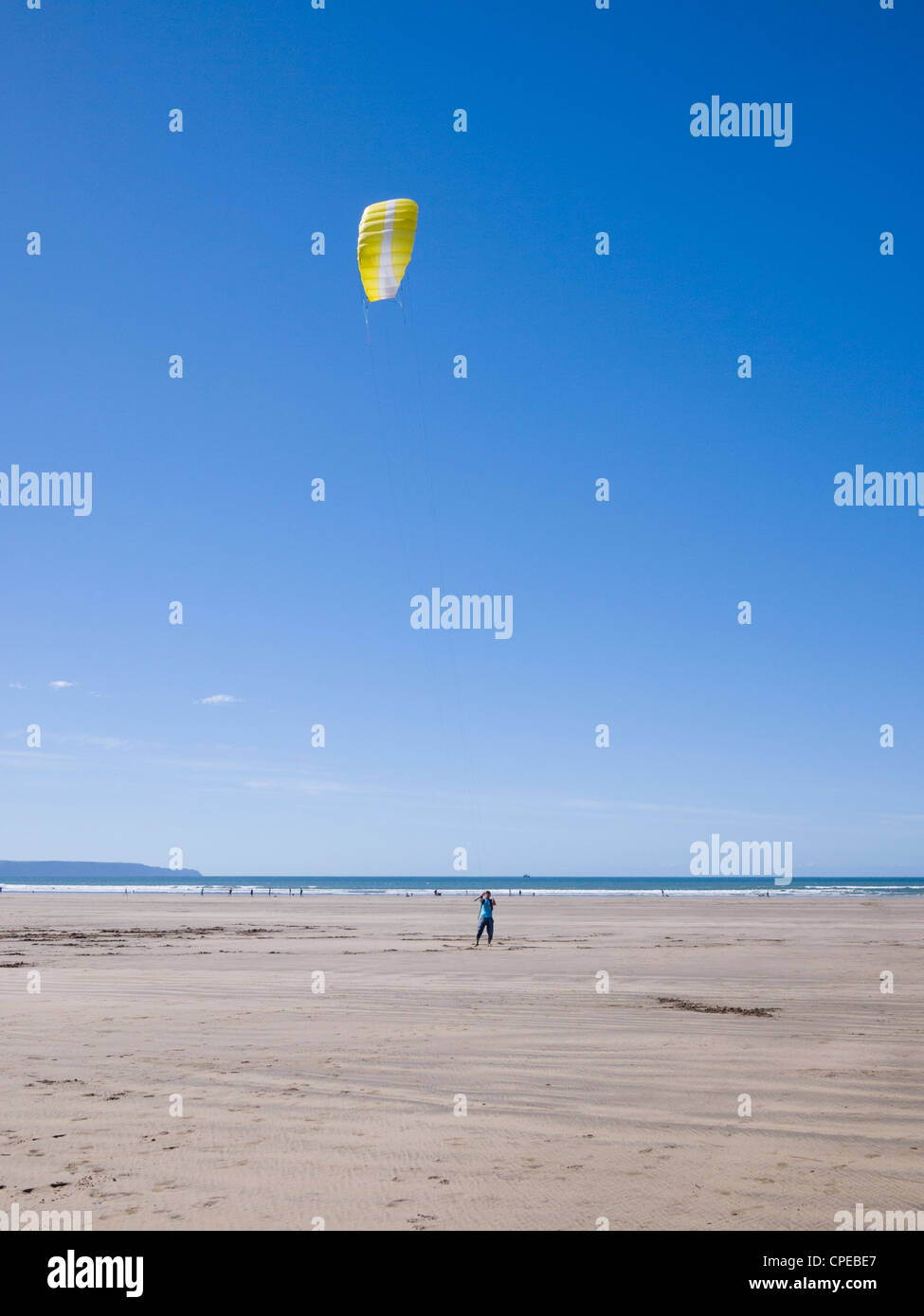 A main flying a yellow traction kite on the beach at Westward Ho!, Devon, England. Stock Photo