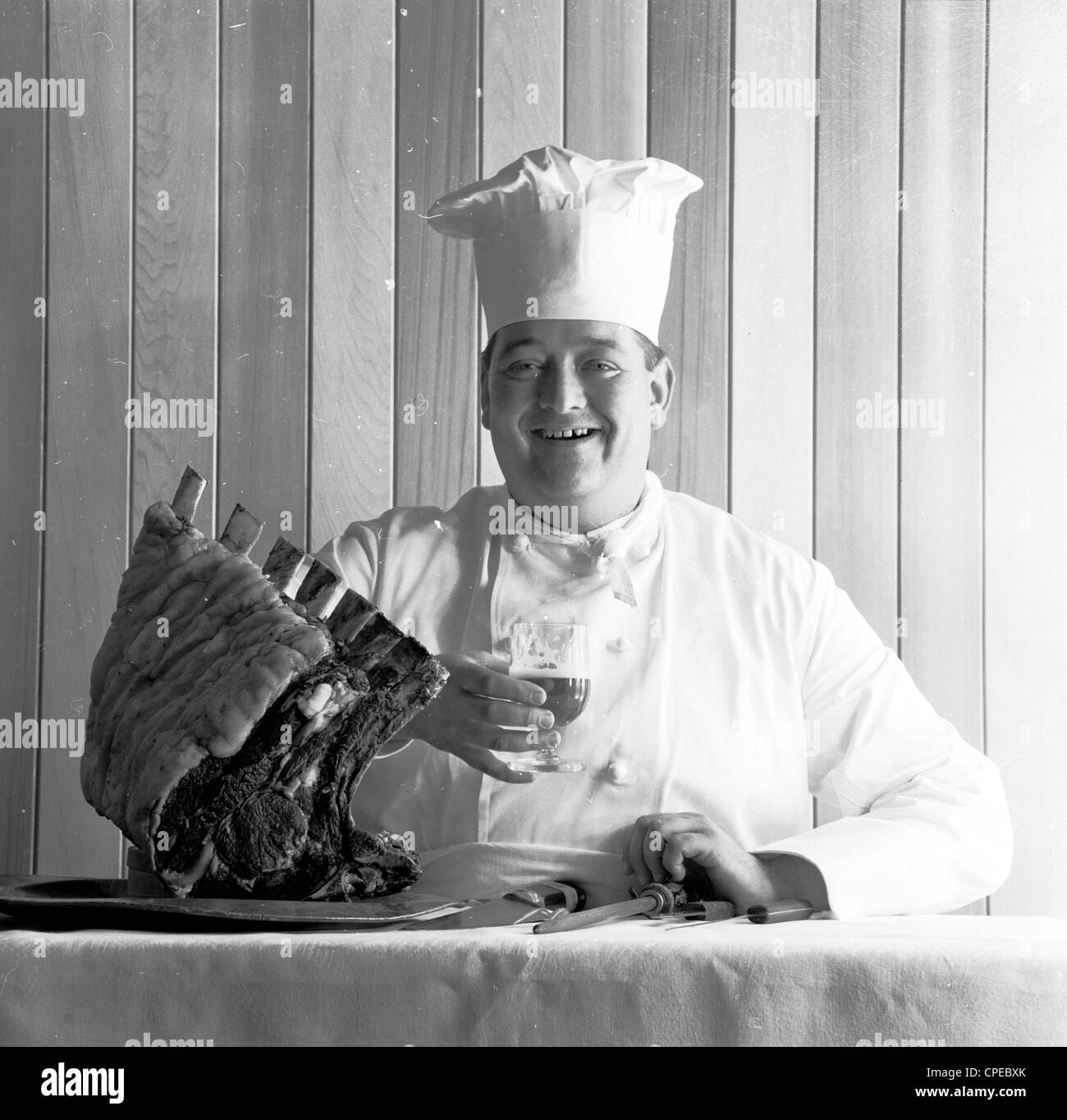 Image from 1960s. A proud chief with drink shows off a large piece of