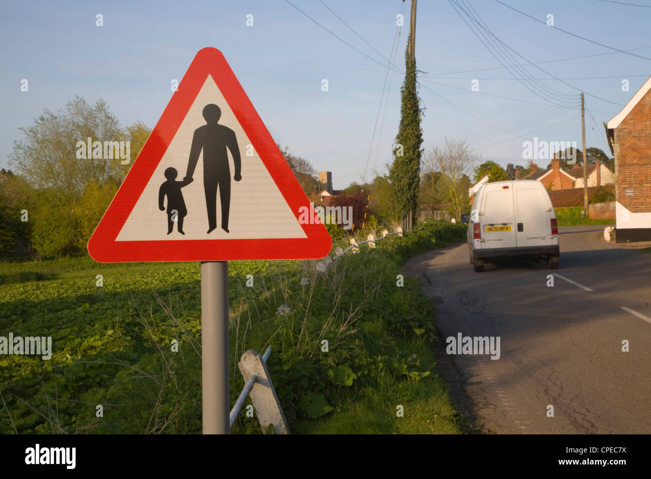 Road sign of adult and child holding hands warns of no pedestrian path through village, Shottisham, Suffolk, England Stock Photo