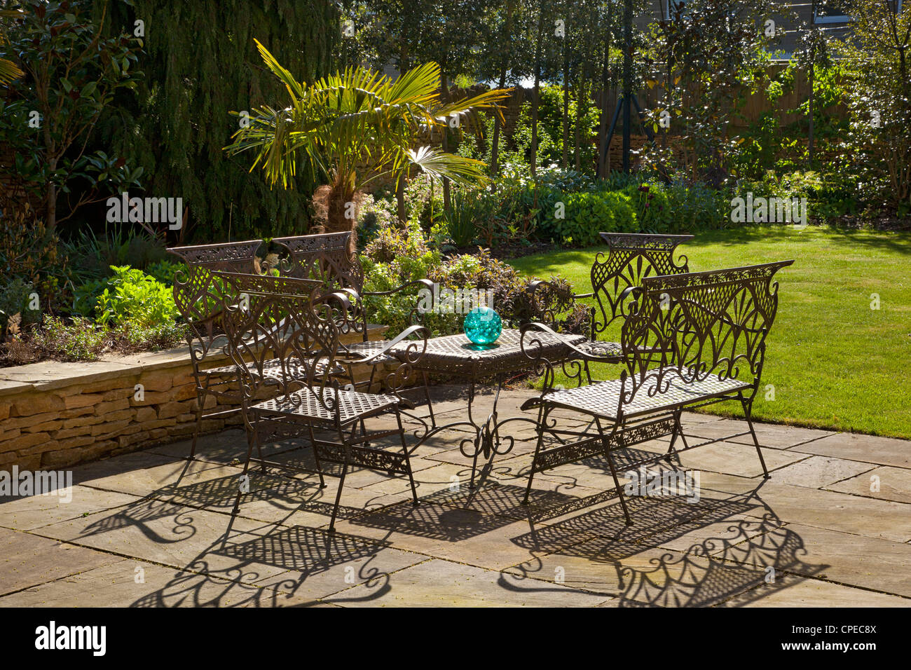 French style metal table and chairs furniture on stone patio in summer garden Stock Photo